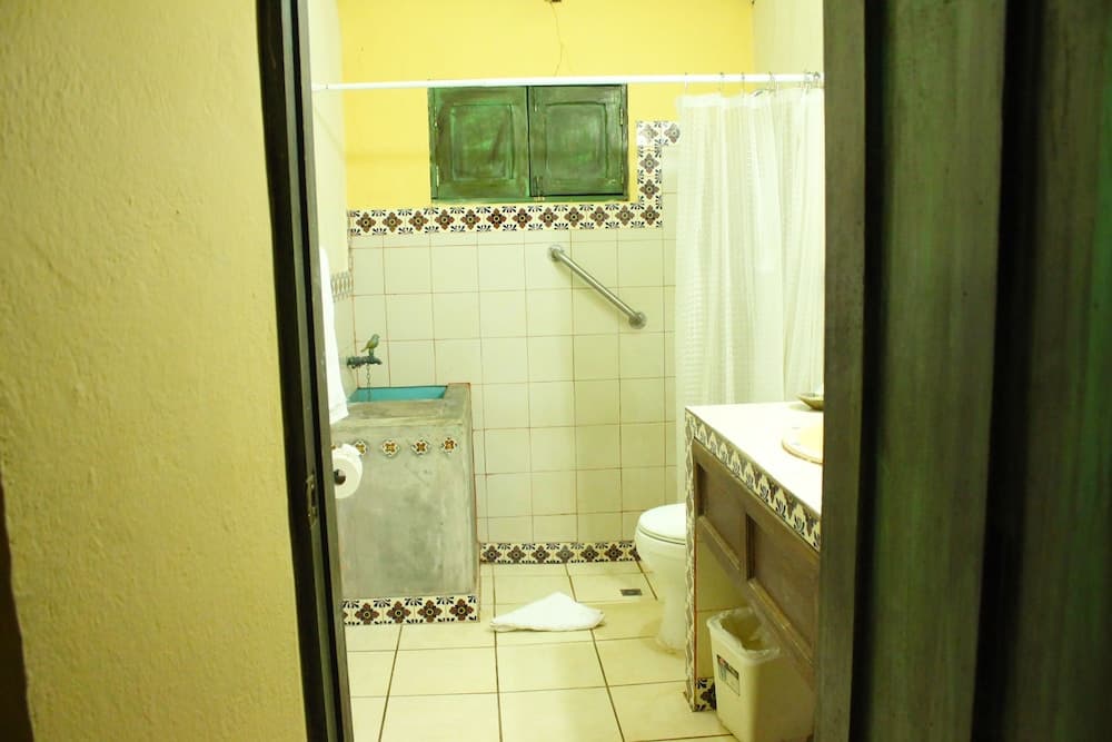 A cozy bathroom with tiled walls, a rustic sink, green cabinets, and decorative tiles exudes a warm, inviting atmosphere ideal for travelers seeking a quaint and functional accommodation.