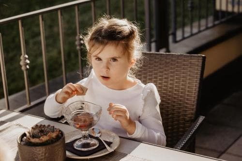 A young girl enjoys a dessert on a cozy outdoor patio, creating a charming family-friendly dining scene perfect for travel blogs focused on child-friendly restaurants.