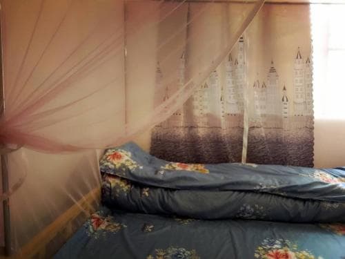 A cozy bedroom features a floral-patterned bed under a whimsical castle-themed curtain, creating an intimate and dreamy atmosphere ideal for travelers seeking a unique and comfortable stay.
