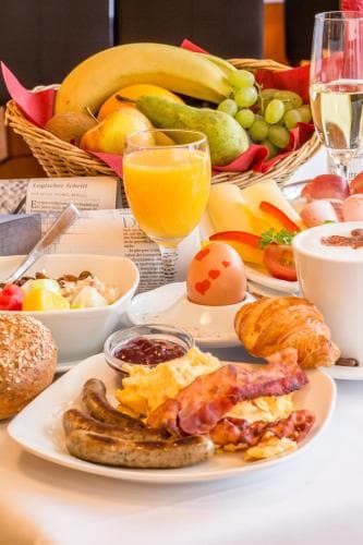 A lavish hotel breakfast spread featuring eggs, bacon, sausages, fresh fruits, croissants, and beverages creates an inviting and indulgent morning atmosphere perfect for travelers seeking comfort and variety.
