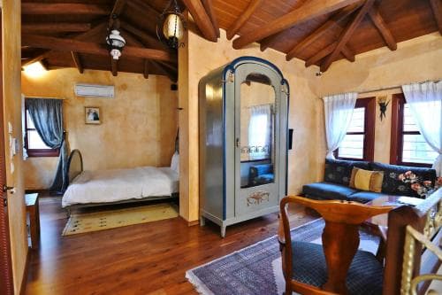 A cozy rustic bedroom with wooden beams, warm-toned walls, and vintage furnishings creates an inviting atmosphere, perfect for travelers seeking a charming and unique accommodation experience.