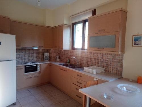 A cozy kitchen with wooden cabinets, tiled backsplash, and natural light from a window creates a warm atmosphere, ideal for travelers seeking a homey rental space.