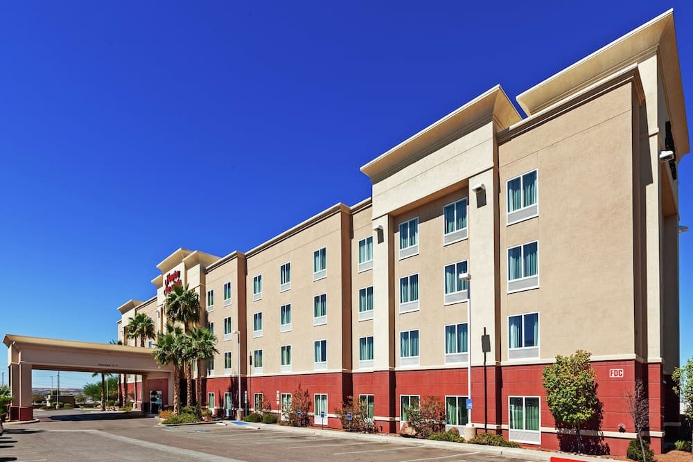 A sunny day highlights a modern multi-story hotel with palm trees and clear blue skies, ideal for travelers seeking comfortable accommodations in a warm climate destination.