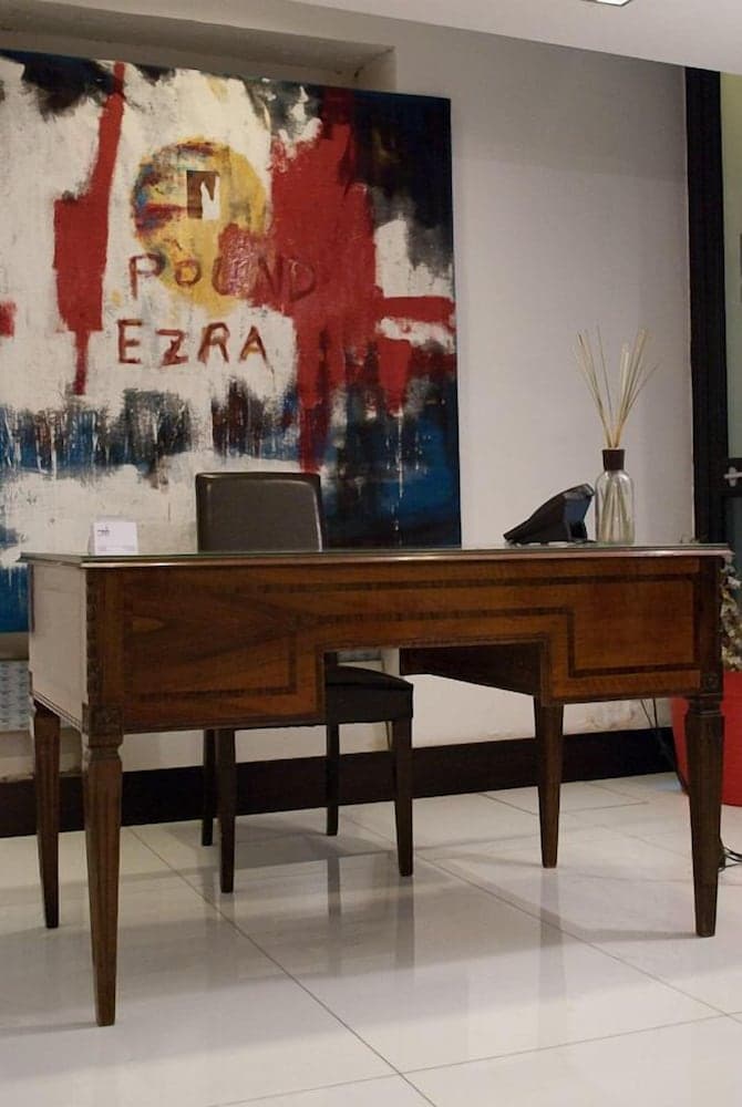 A modern hotel lobby exudes sophistication with a polished wooden desk, abstract art featuring "Pound Ezra," and minimalist decor, ideal for travelers seeking a stylish check-in experience.