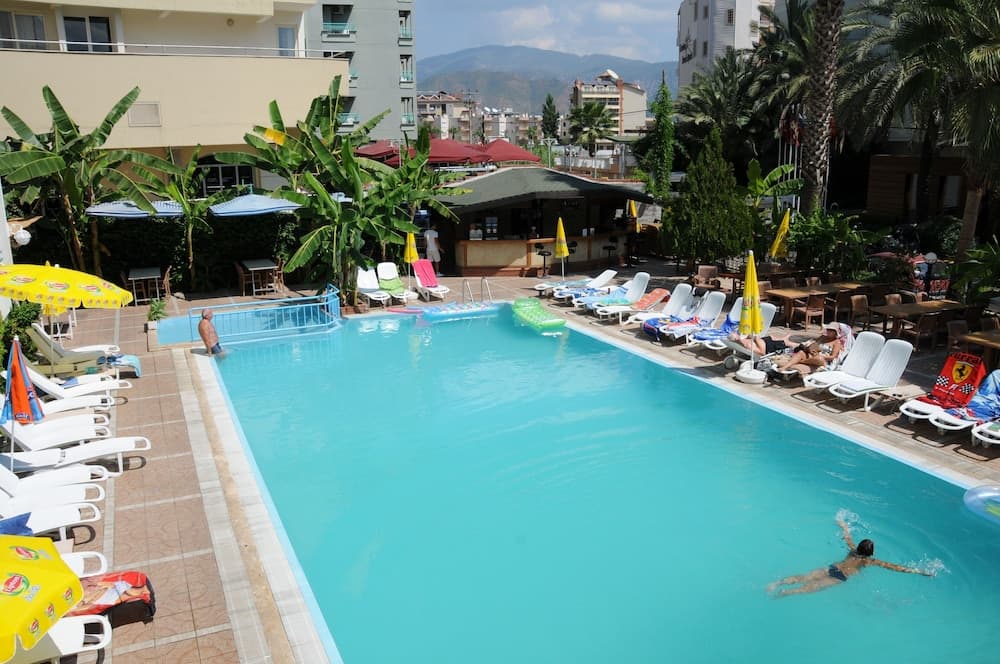 A vibrant resort pool surrounded by lounge chairs, colorful umbrellas, and lush greenery offers a relaxing atmosphere ideal for vacationers seeking leisure and recreation.