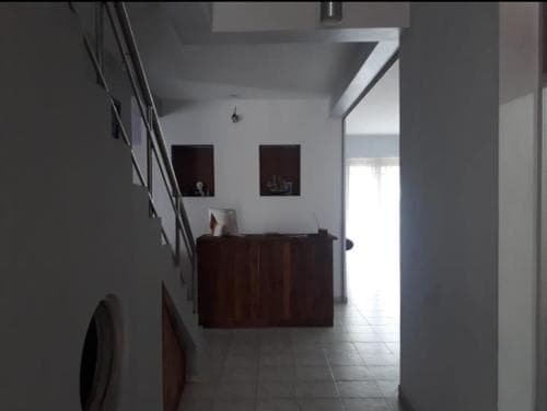 A minimalist indoor hallway with tiled floors, a wooden cabinet, and framed wall art creates a serene atmosphere, ideal for travelers seeking a quiet accommodation space.