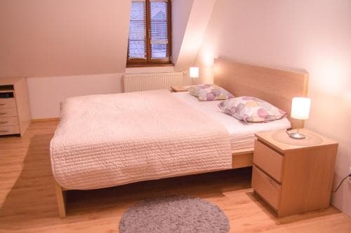 A cozy bedroom with wooden furnishings, soft lighting, and a window view offers a serene retreat for travelers seeking comfort and relaxation.