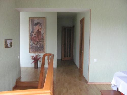 A cozy indoor hallway with light green walls, wooden flooring, a staircase railing, and framed artwork creates a welcoming atmosphere ideal for a home stay or vacation rental listing.