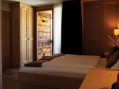 A cozy wooden cabin bedroom with warm lighting, rustic decor, and a neatly made bed invites travelers seeking a serene retreat in nature.