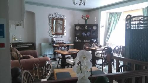 A cozy, vintage-style dining area with ornate mirrors, wooden furniture, and floral arrangements creates an inviting atmosphere perfect for travelers seeking a charming and relaxed meal spot.
