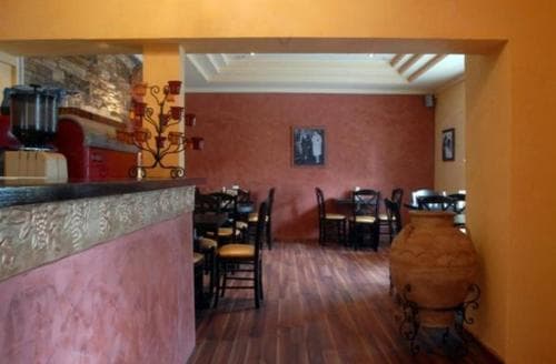 A cozy restaurant interior with warm terracotta walls, wooden floors, and rustic decor creates an inviting atmosphere, perfect for travelers seeking a charming dining experience.