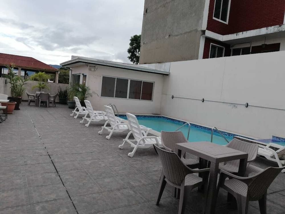 A serene rooftop pool area with lounge chairs, potted plants, and a cozy seating nook offers a relaxing retreat for travelers seeking a peaceful getaway.