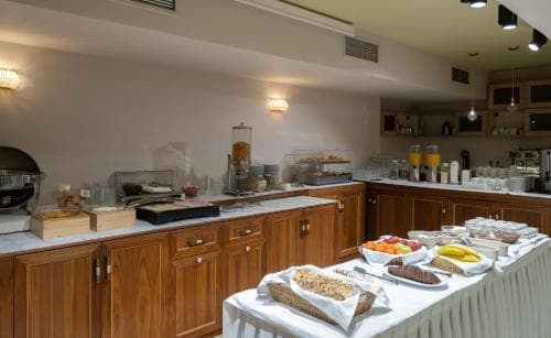 A cozy hotel breakfast area features a well-organized buffet with fresh pastries, fruits, and beverages, inviting travelers to start their day in a warm and welcoming atmosphere.