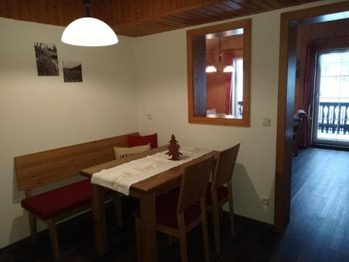 A cozy dining area with wooden furniture, festive decor, and warm lighting invites travelers to relax in a charming cabin setting, perfect for a winter getaway.