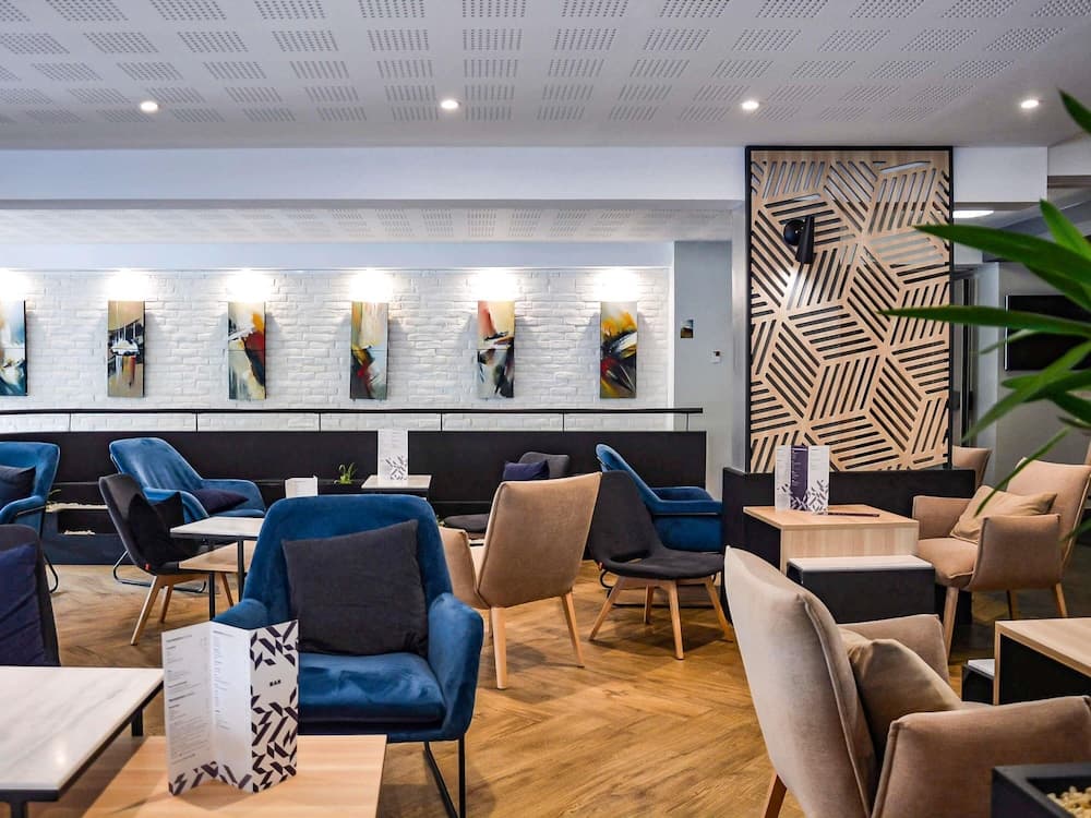 A cozy hotel lounge features modern seating, artistic wall decor, and warm lighting, creating an inviting atmosphere ideal for travelers seeking relaxation or business meetings.