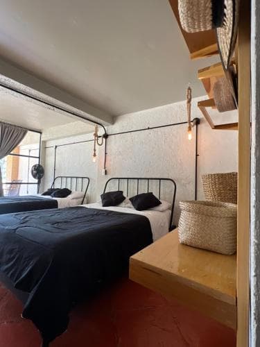 A cozy, modern hostel room with two neatly made beds, rustic wooden furniture, and warm lighting creates an inviting atmosphere perfect for budget travelers seeking comfort and style.