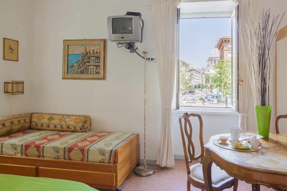 A cozy apartment room with a wooden bed, vintage TV, and a scenic view of a domed building through the window, ideal for travelers seeking comfort and charm in an urban setting.