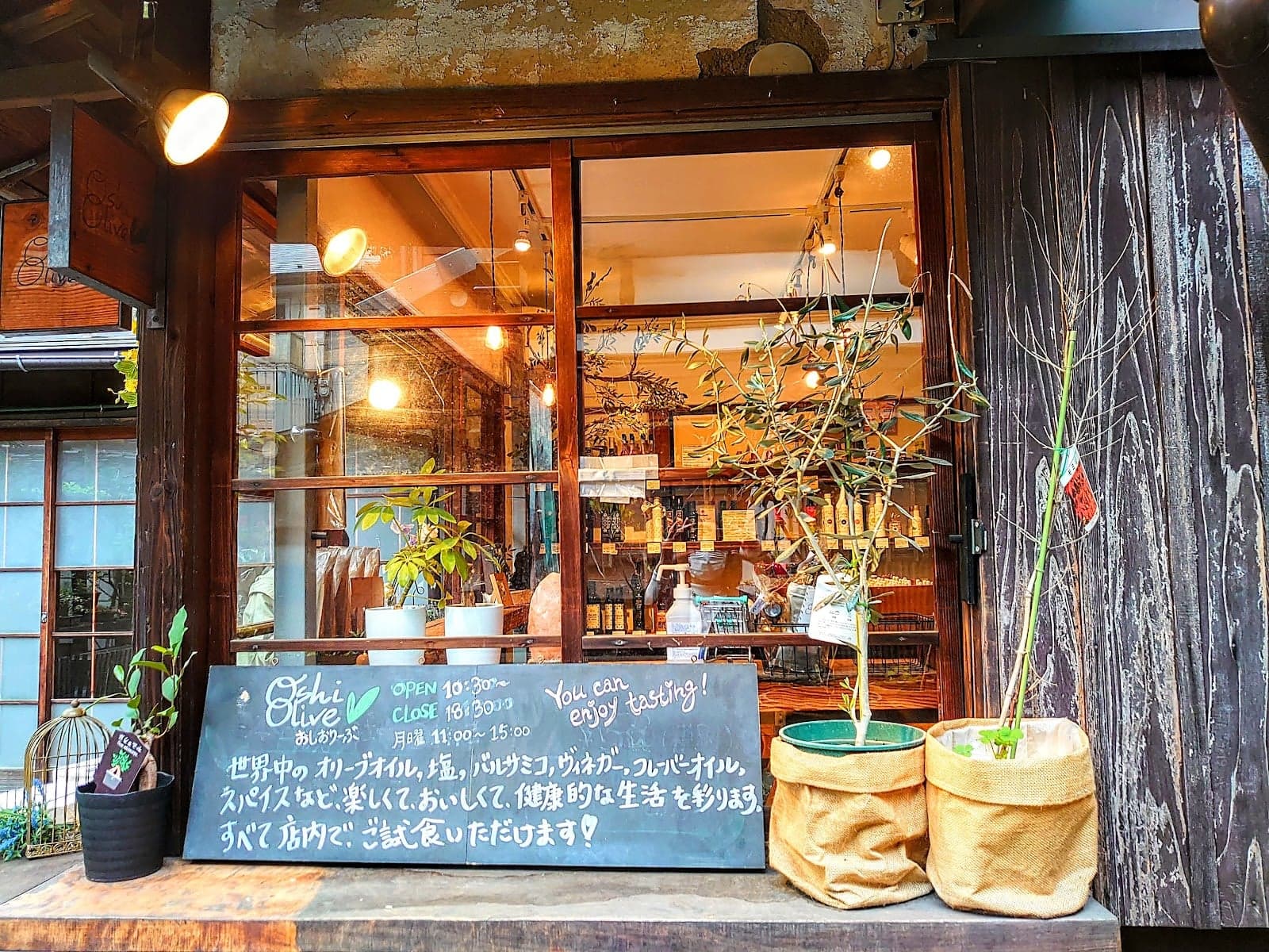 A cozy, rustic olive oil shop in Tokyo's Uenosakuragi neighborhood invites travelers to enjoy tastings of its artisanal products amidst charming wooden decor and potted plants.