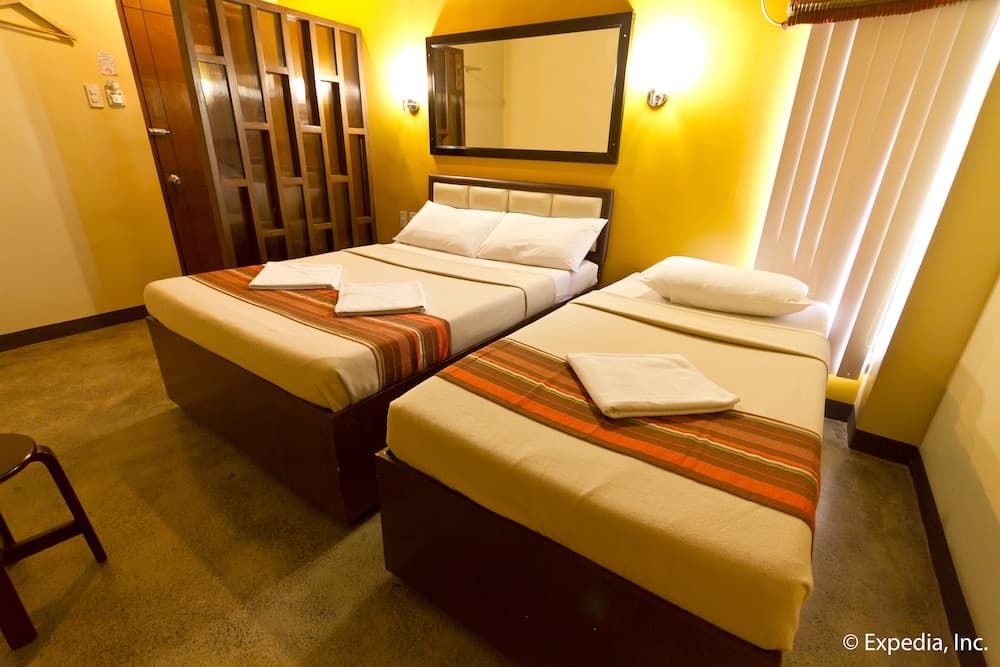 A cozy hotel room with two neatly arranged beds, warm yellow walls, and modern furnishings creates an inviting atmosphere ideal for travelers seeking comfort and relaxation.