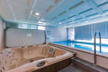 A serene indoor spa scene featuring a luxurious hot tub beside a tranquil pool, ideal for relaxation and wellness retreats.