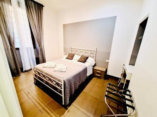A cozy hotel room with a neatly made bed, tiled floors, and modern furnishings offers a comfortable stay for travelers seeking relaxation.