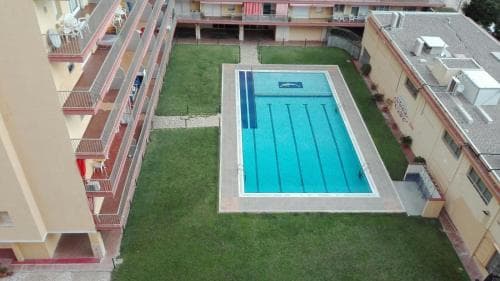 An aerial view of a serene residential complex featuring a vibrant blue swimming pool surrounded by lush greenery, ideal for travelers seeking a relaxing vacation spot.