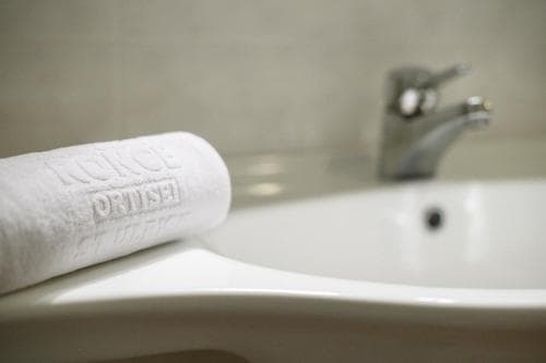 A serene hotel bathroom scene features a neatly folded towel with embossed text beside a modern sink and faucet, ideal for travelers seeking comfort and cleanliness.