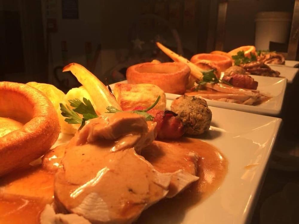 A cozy restaurant setting features a sumptuous spread of roasted turkey, Yorkshire pudding, and seasonal vegetables, perfect for a festive dining experience.