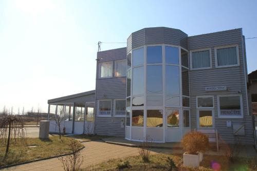 A modern, multi-story house with large glass windows stands in a serene suburban setting under a clear blue sky, ideal for travelers seeking a quiet retreat with contemporary accommodations.