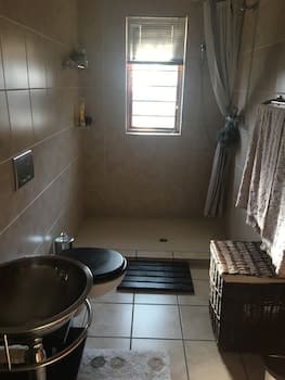 A serene bathroom with tiled walls, a window letting in natural light, a sleek sink, and a woven basket adds a cozy touch, ideal for travelers seeking relaxation and comfort during their stay.