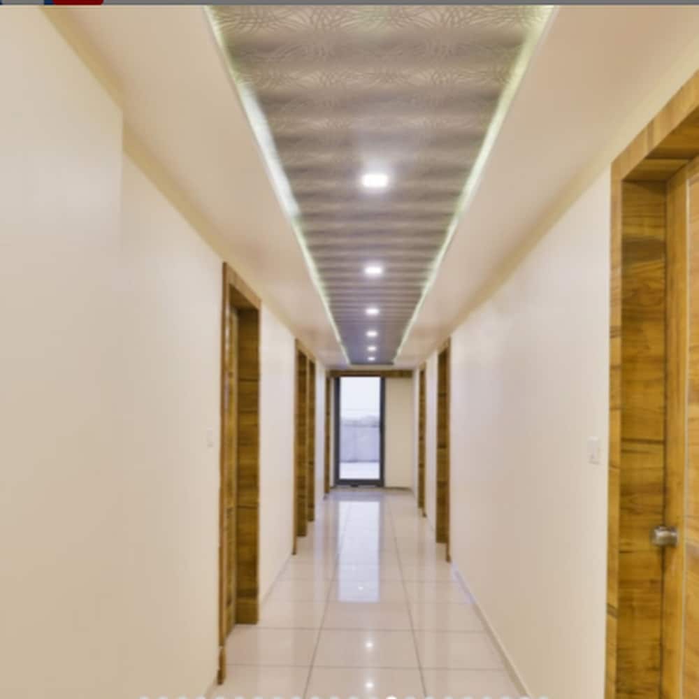A well-lit hotel corridor with wooden doors and tiled floors creates a clean and inviting atmosphere, ideal for travelers seeking comfortable accommodations.