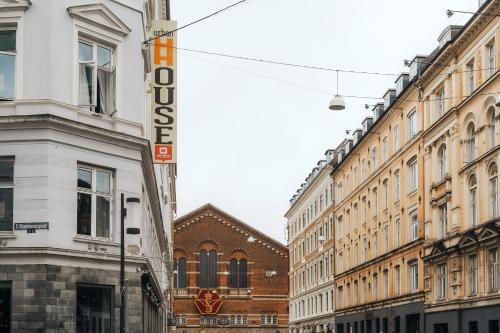 A charming European street scene featuring historic architecture, a vibrant "Urban House" sign, and a church with a red emblem, ideal for urban exploration and cultural tourism.