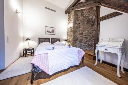 A cozy bedroom with rustic stone walls, wooden beams, and soft lighting creates an inviting atmosphere, perfect for travelers seeking a charming and serene retreat.