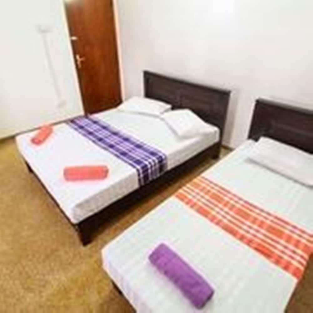 A cozy budget-friendly hotel room features two neatly made single beds with colorful striped sheets, set against plain walls, ideal for travelers seeking simple accommodations.