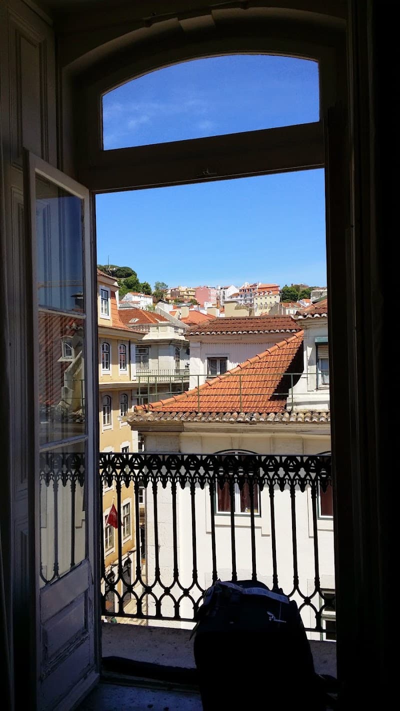 A serene balcony view from Lisbon RiverView Hostel showcases vibrant red-tiled roofs under a clear blue sky, ideal for travelers seeking a picturesque urban retreat in Lisbon.