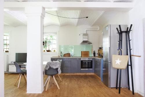 A cozy open-plan kitchen and dining area with wooden floors, modern appliances, and natural light creates an inviting atmosphere ideal for a family vacation rental.