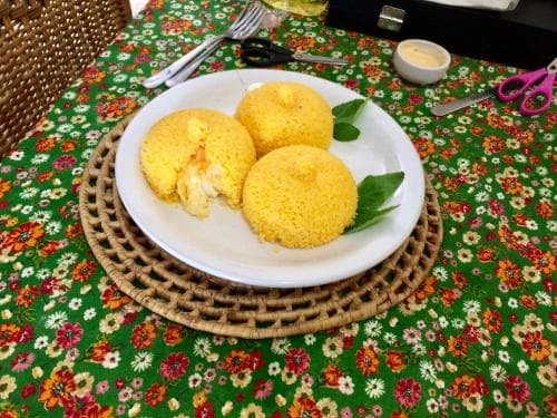 A cozy dining table adorned with a vibrant floral tablecloth sets the stage for a delightful meal featuring golden corn cakes on a white plate, perfect for travelers seeking authentic local cuisine experiences.