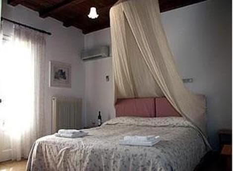 A cozy bedroom with a canopy bed draped in soft fabric, featuring natural light from sheer curtains, exudes a serene and inviting atmosphere ideal for a relaxing getaway.
