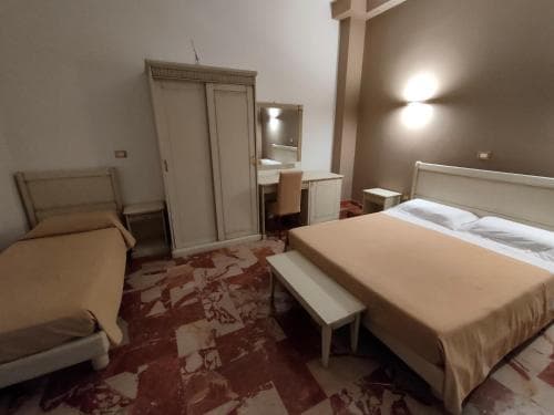 A cozy hotel room features a neatly made bed, a vanity with a mirror, and warm lighting, creating an inviting atmosphere ideal for travelers seeking comfort and relaxation.