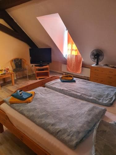A cozy attic bedroom with slanted ceilings, wooden furniture, and warm lighting creates an inviting atmosphere, perfect for travelers seeking a quaint and comfortable stay.