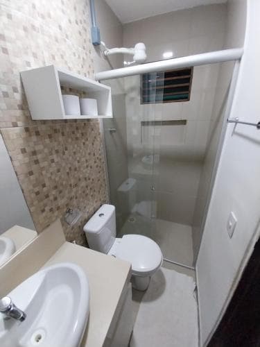 A compact bathroom with tiled walls, a sink, toilet, and shower area offers a clean and functional space ideal for travelers seeking efficient accommodations.