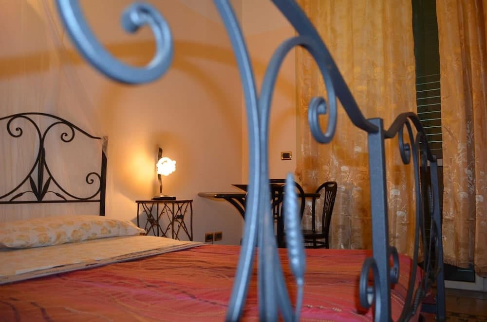 A cozy bedroom with ornate wrought iron bed frames, warm yellow curtains, and soft lighting creates an inviting atmosphere ideal for travelers seeking a charming and intimate accommodation experience.