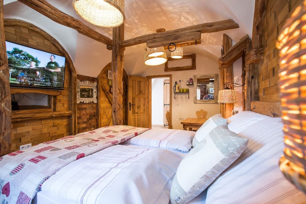 A cozy rustic bedroom with wooden beams, warm lighting, and a comfortable bed invites travelers seeking a serene retreat in a charming lodge setting.