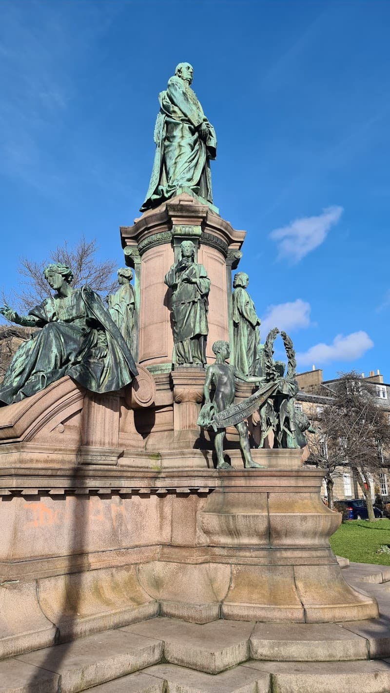 A majestic statue ensemble stands proudly under a clear blue sky in a serene park setting at Atholl Crescent in Edinburgh, inviting travelers to explore its historical significance and architectural beauty.