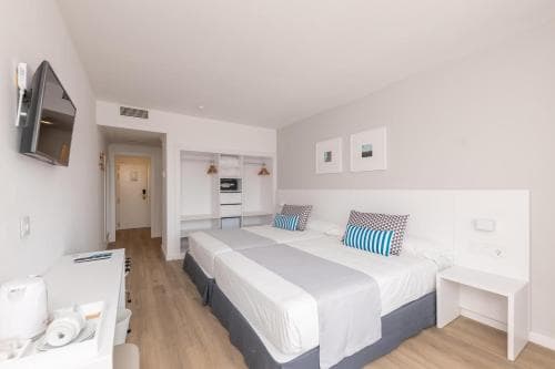 A cozy hotel room with two neatly made beds, modern decor, and a small desk exudes a clean and inviting atmosphere, perfect for travelers seeking comfort and simplicity during their stay.