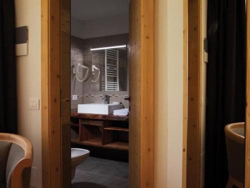A cozy hotel bathroom with wooden accents, modern fixtures, and a neatly arranged vanity area, ideal for travelers seeking comfort and style in their accommodations.
