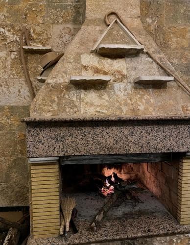A cozy indoor fireplace scene with glowing embers and rustic stone shelves evokes warmth and relaxation, ideal for travelers seeking a traditional and intimate atmosphere in a heritage setting.