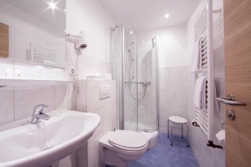 A modern, clean hotel bathroom with a glass-enclosed shower, sleek white fixtures, and wooden accents creates a cozy and inviting atmosphere ideal for travelers seeking comfort and convenience.