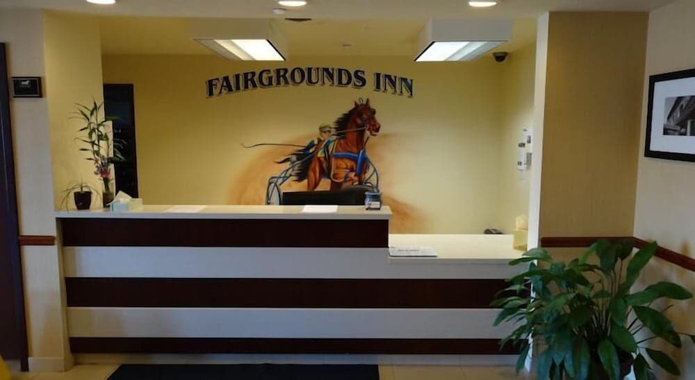 The welcoming lobby of Fairgrounds Inn features a vibrant mural of a horse and rider, potted plants, and a reception desk, ideal for travelers seeking a cozy and inviting accommodation experience.