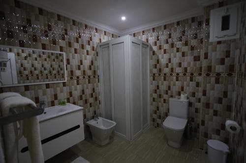 A cozy hotel bathroom features warm-toned mosaic tiles, a modern shower stall, and neatly arranged fixtures, ideal for travelers seeking comfort and cleanliness during their stay.